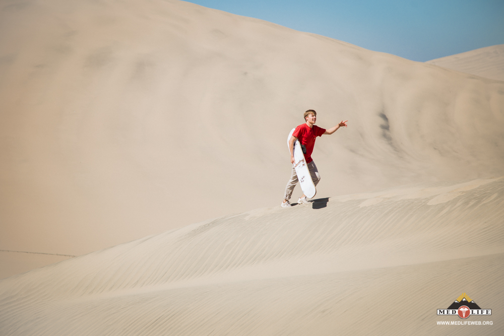 One of the high school volunteers climbs sand dunes during the day trip to Ica.